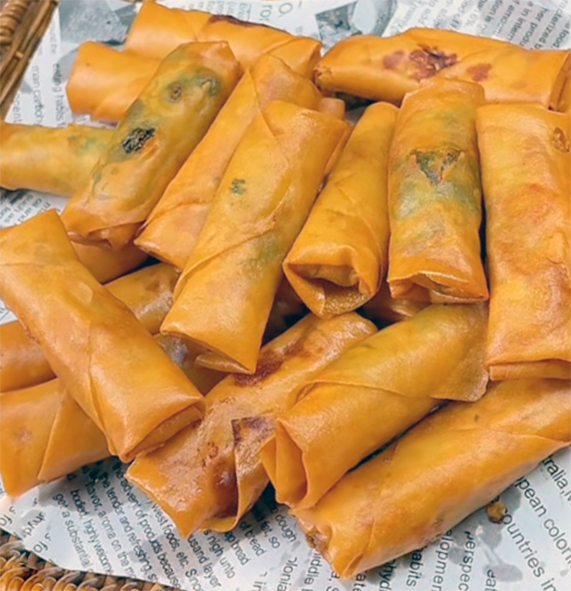 Chinese crispy fried spring rolls on a wooden tray covered with a cloth.