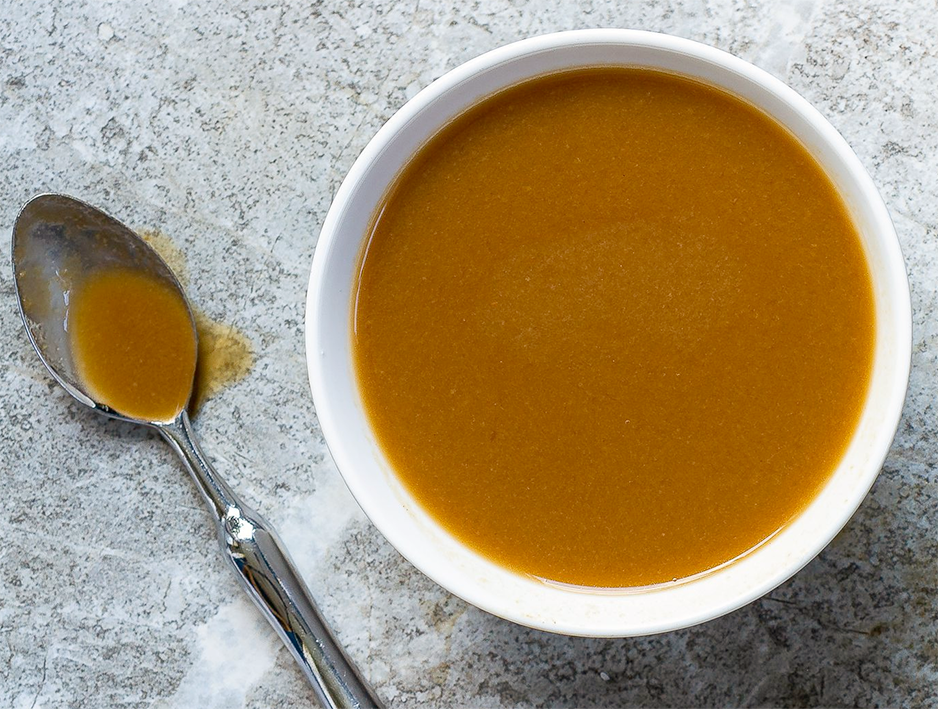 demi-glace sauce in a white ramekin with a spoon containing sauce to the side