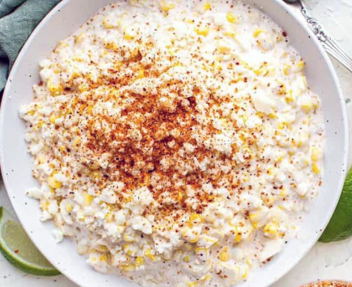 esquites on a plate with a topping of queso fresco and chili powder
