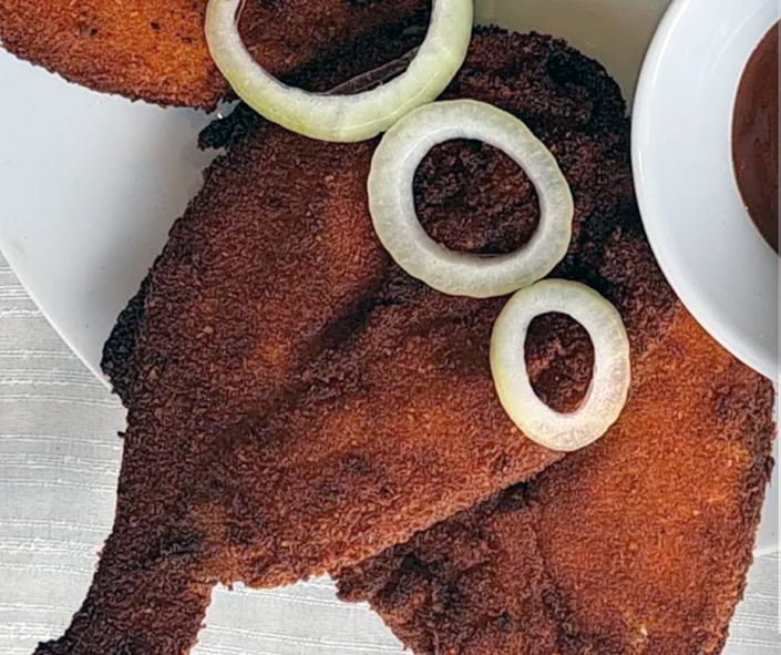 sierra leonean crisp-fried breaded butterflied fish with onion ring garnish