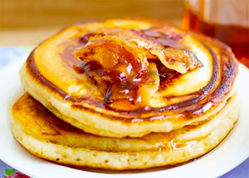 two american pancakes topped with bacon and maple syrup