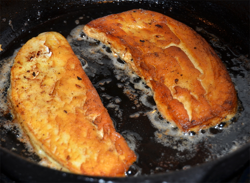 giant puffball slices coated in egg frying in a cast iron pan