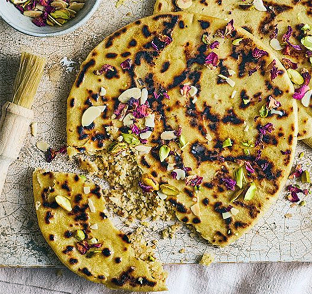 dried fruit and nigella seed naan bread with the end torn off on a sheet of linolium