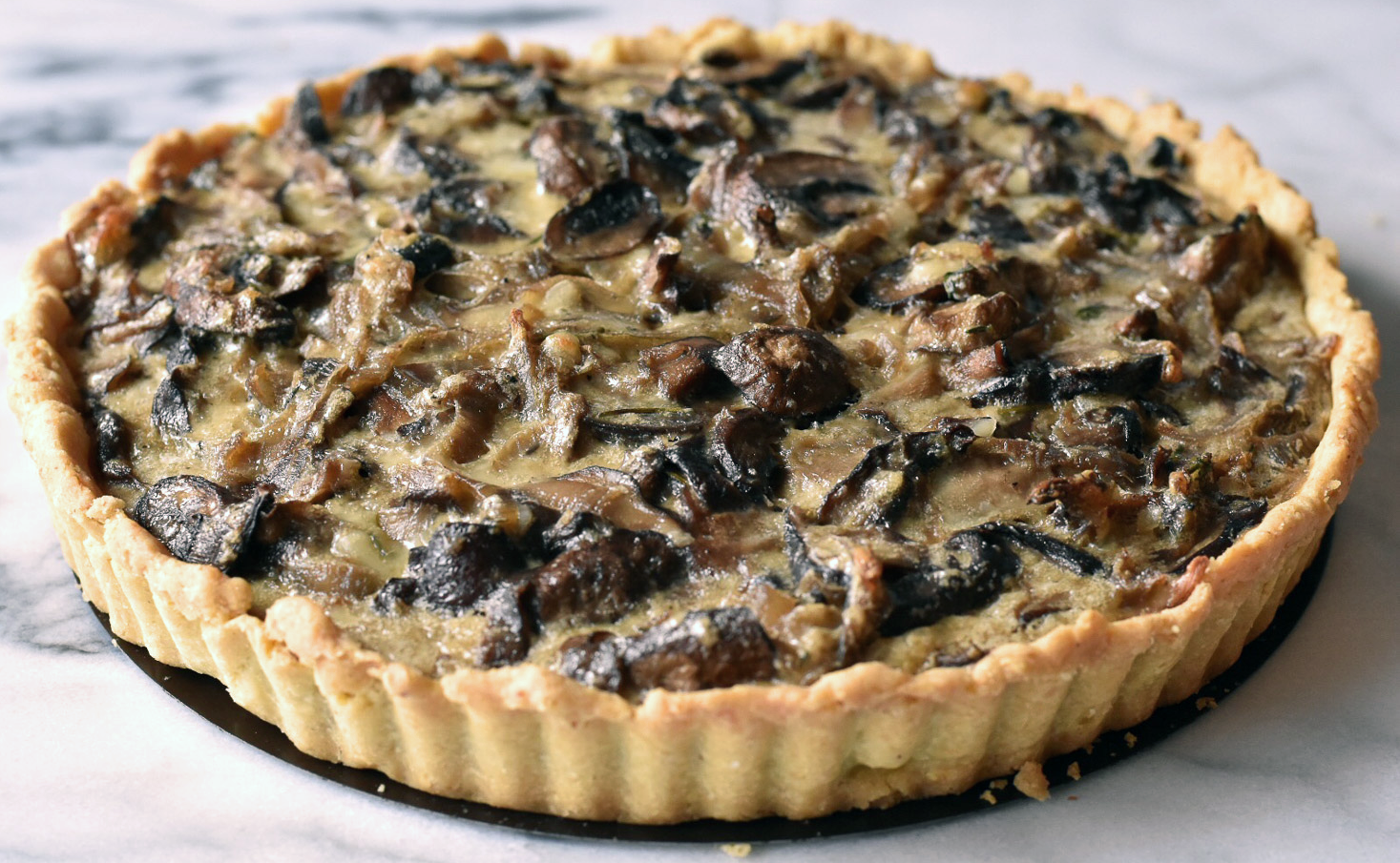 tart with a honey fungus, egg and tomato puree filling shown on a marble worktop