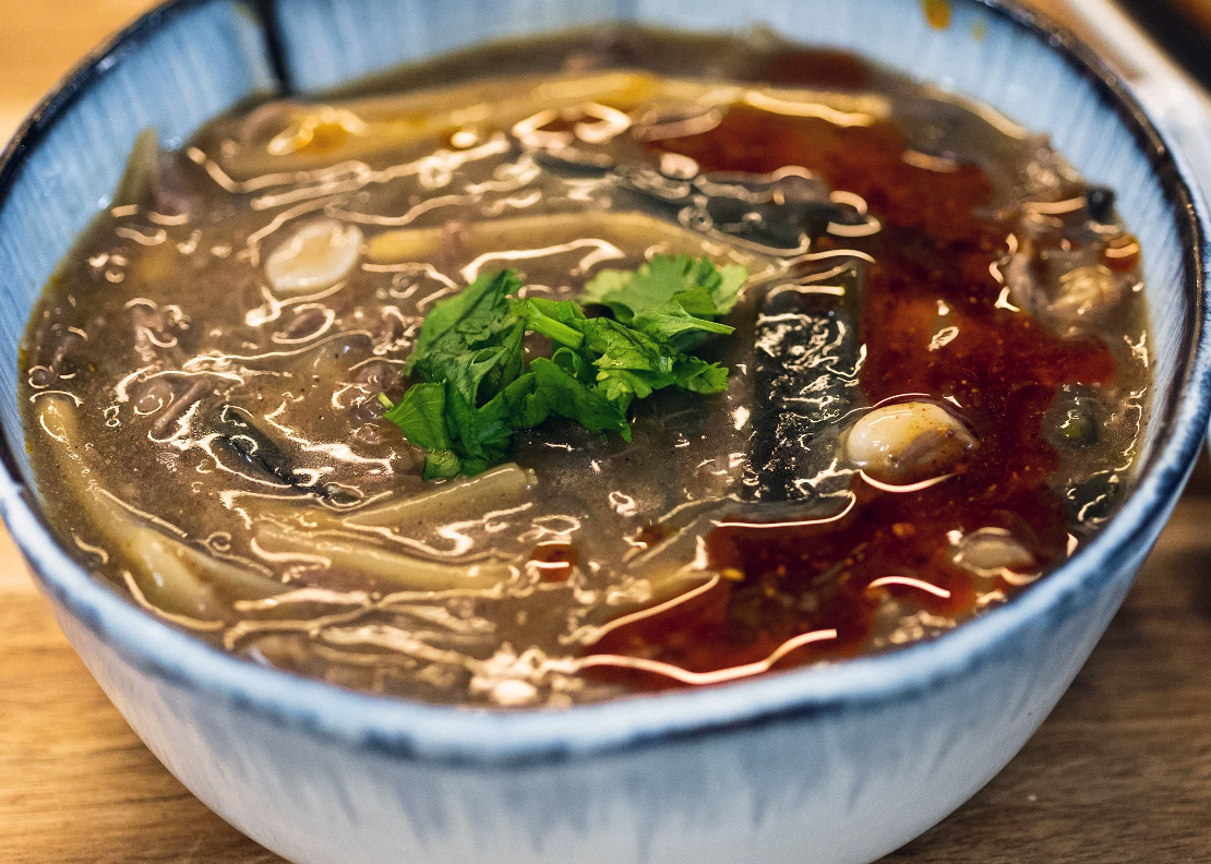 Chinese hot pepper soup in a bowl with noodles and 