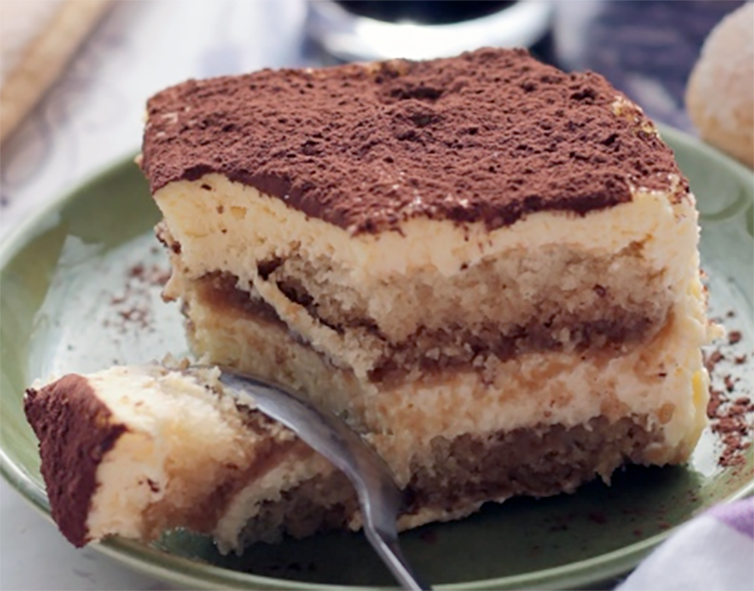 square of il mio tiramisu served on a green plate with a spoon</em>