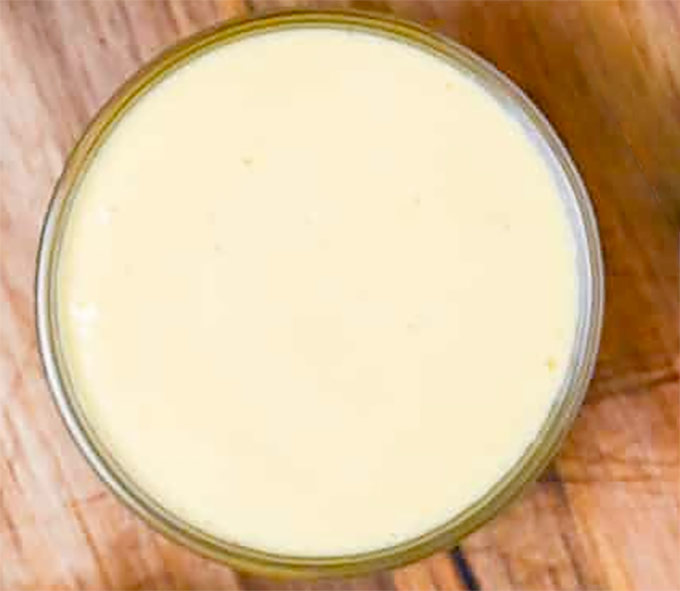 Japanese kewpie mayonnaise in a glass bowl on a wooden chopping board