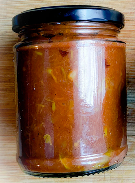 japanese knotweed jam in a glass jar against a wood grain table