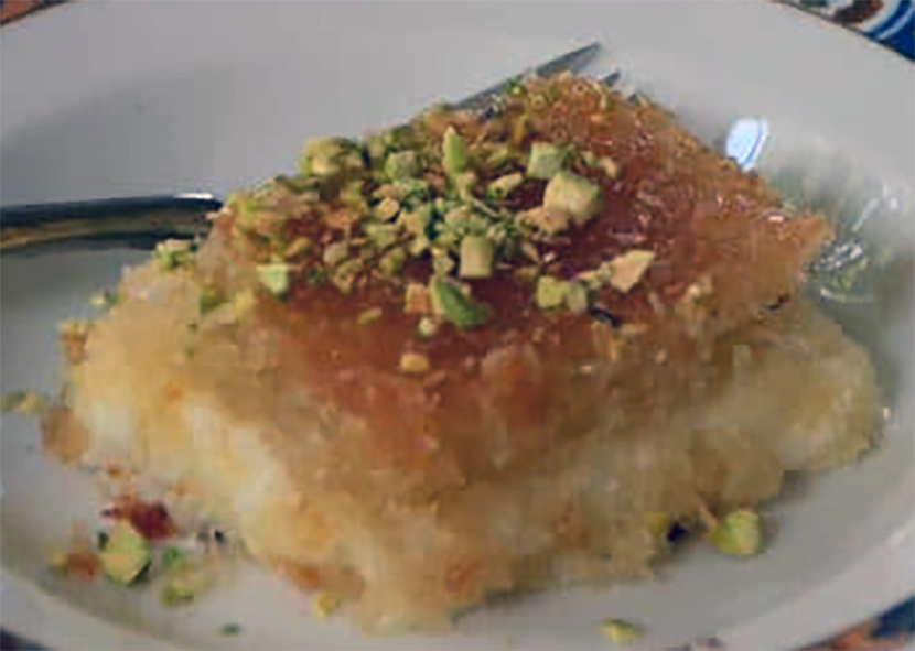 slice of knafeh on a plate with a garnish of pistachio nuts