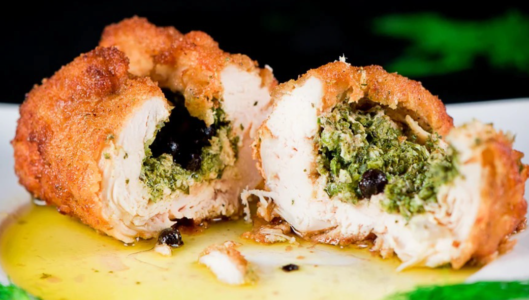 chicken kiev split in half on a plate with the butter filling spilled out in front