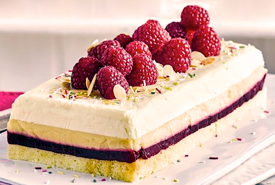 a layered chilled trifle cake of cream, custard, jelly and sponge layers served topped with raspberries and flaked almonds