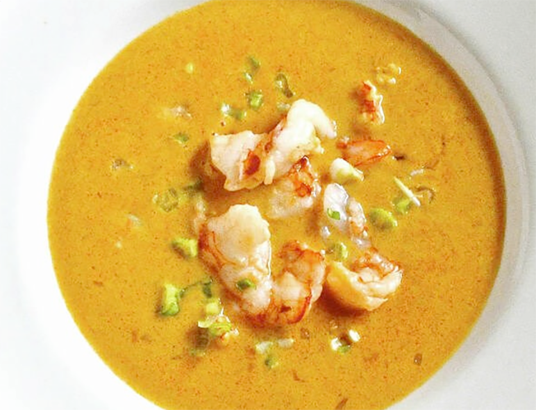 prawn bisque served in a soup bowl with a garnish of chopped prawns