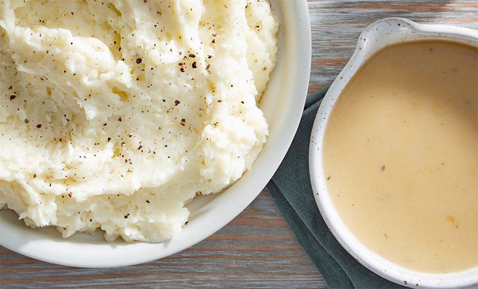 bowl of mashed potatoes next to a jug of gravy
