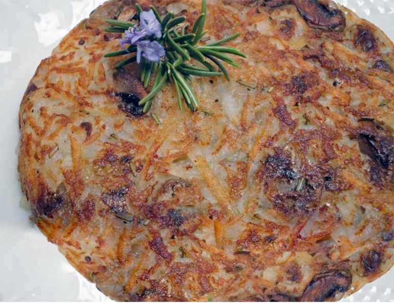 large morel mushroom rosti with a flowering thyme sprig garnish presented on a white plate