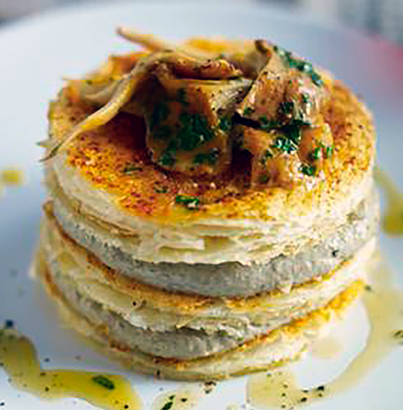 laters of puff pastry with a mushroom filling served topped with chanterelle mushrooms
