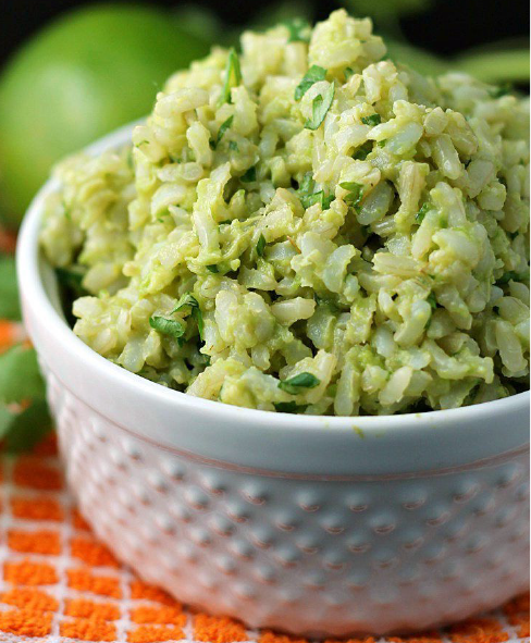 rice pilaf with avocado leaf served in a white bowl with limes in the background
