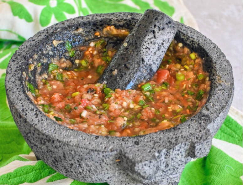 salsa molcajete of chillies, tomatoes, spring onions and garlic prepared and served in a granite mortar