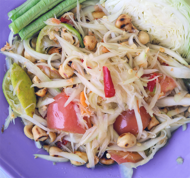 thai green papaya salad with tomatoes, and roasted peanuts served with cabbage on a plate