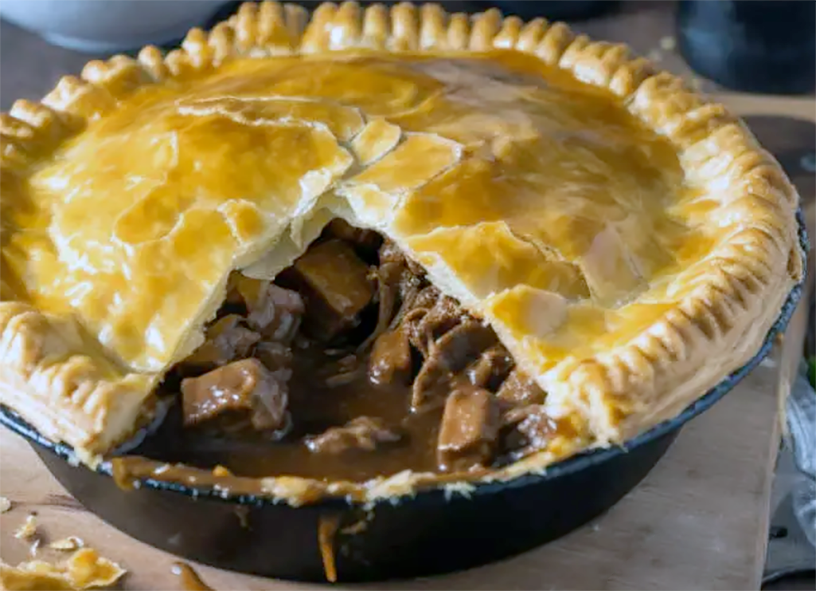 steak and ale pie shown with a wedge removed to reveal the filling