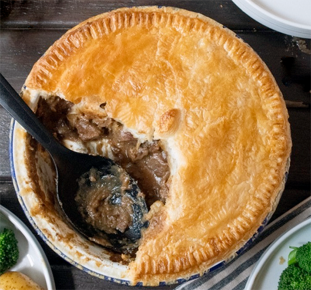 steak and kidney pie on a table with a wedge removed