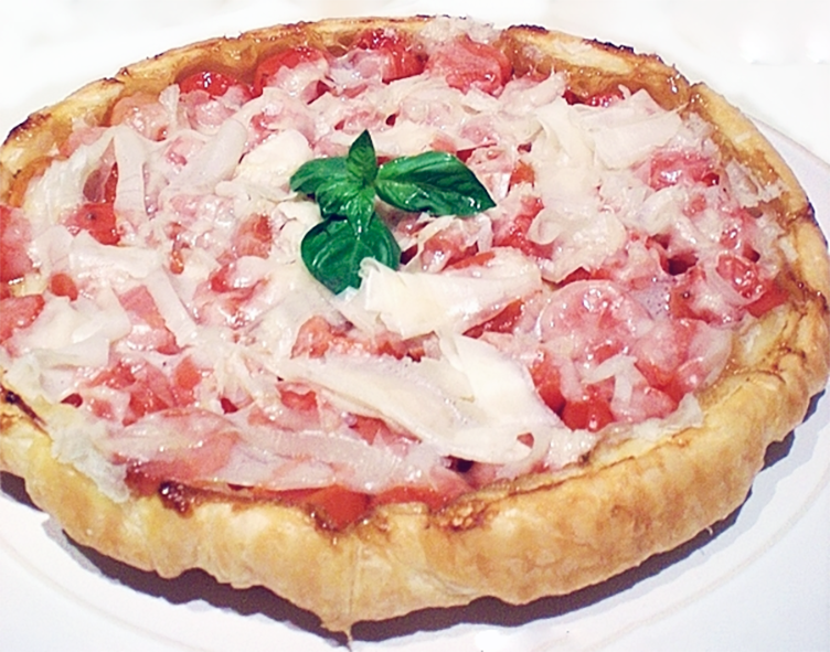 tomato and mozzarella cheese on a tarte tatin base garnished with a sprig of basil