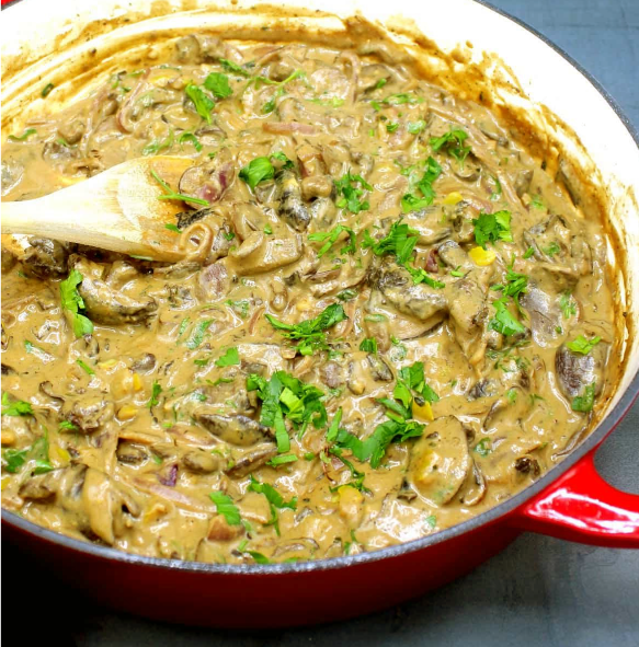 vegan mushroom stroganoff stirred in a casserole dish with a wooden spoon