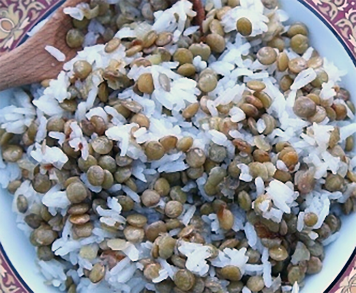 lentil and onion pilaf served on a plate with a wooden spoon