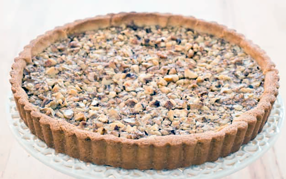 walnut tart on a white cast iron cake stand