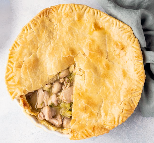 wild mushroom and chicken pie with a chicken cloth shown in a deep pie dish with a section of the top pastry removed to reveal the filling