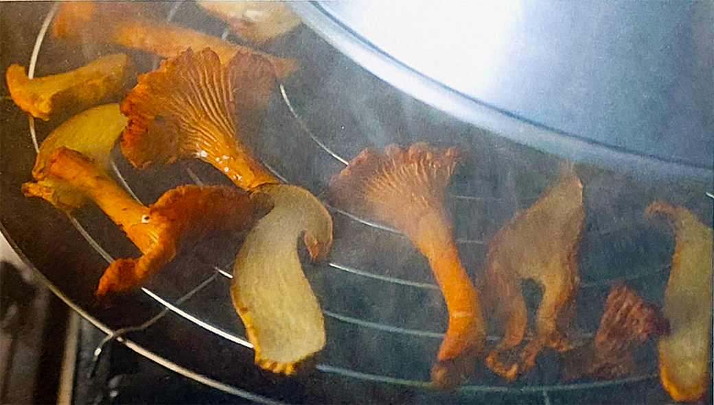 mushrooms smoking on a grill set in a wok