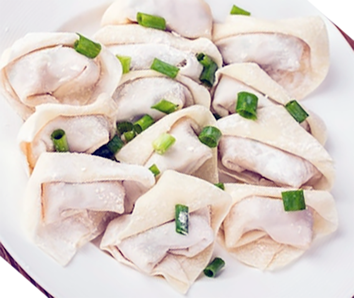 wonton dumplings served on a white plate with sliced spring onion garnish