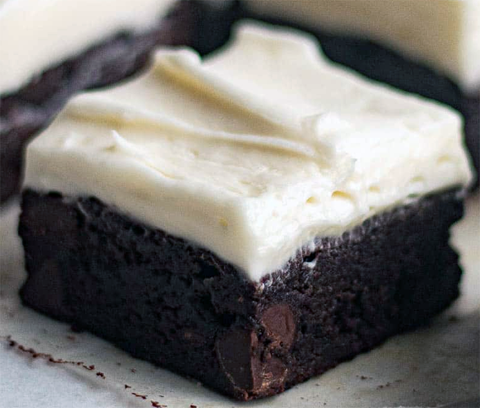 cream cheese frosted A+ brownie on a sheet of greaseproof paper