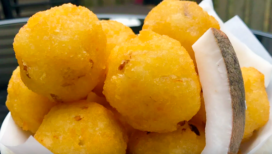 sweet cassava fritter balls served with slices of coconut flesh