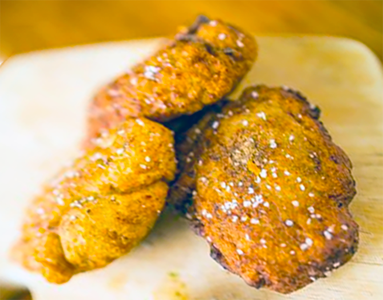 three fried akara fritters arranged on a wooden chopping board
