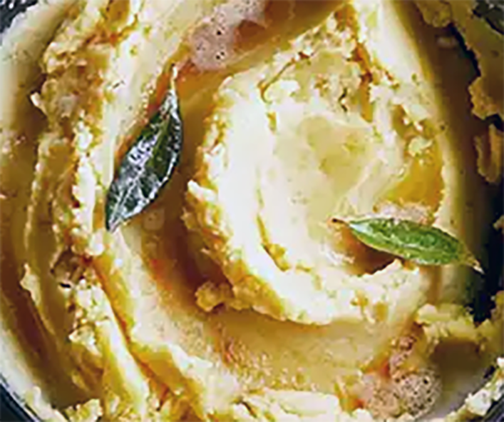 Apple mash swirled in a bowl with two fried sage leaves to garnish