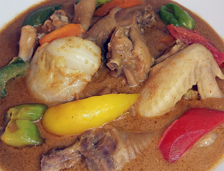 chicken and vegetables in peanut sauce served in a dish