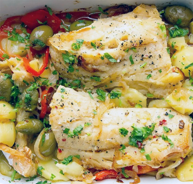 two fillets of salt cod in a baking dish with potatoes, olives and bell peppers