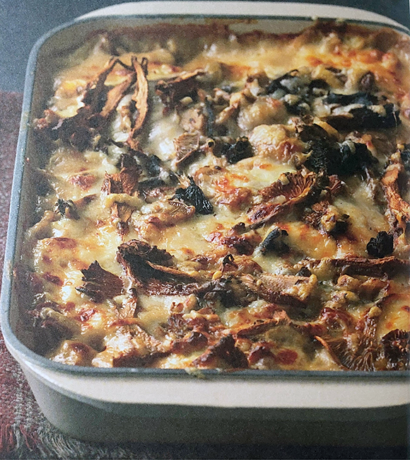 baked wild mushrooms with polenta and a cheese topping shown in a baking dish