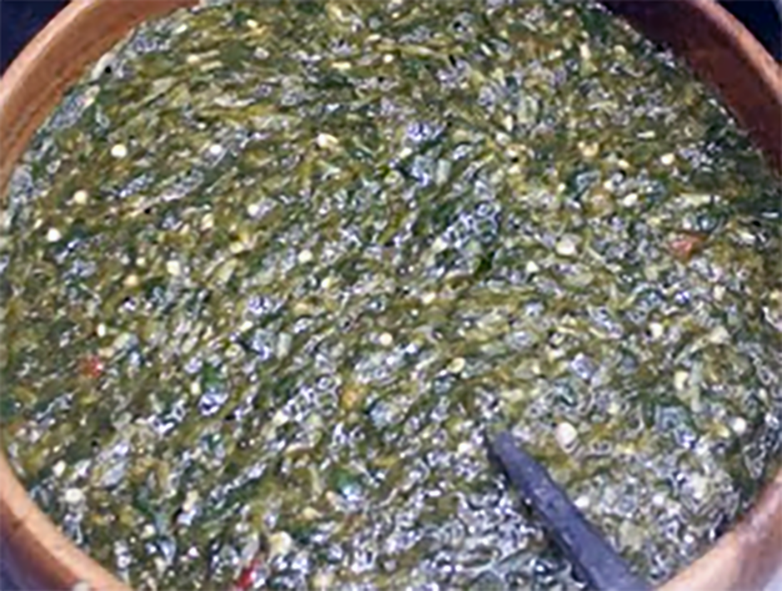 green bissap (hibiscus) beguedji sauce served in an earthenware bowl