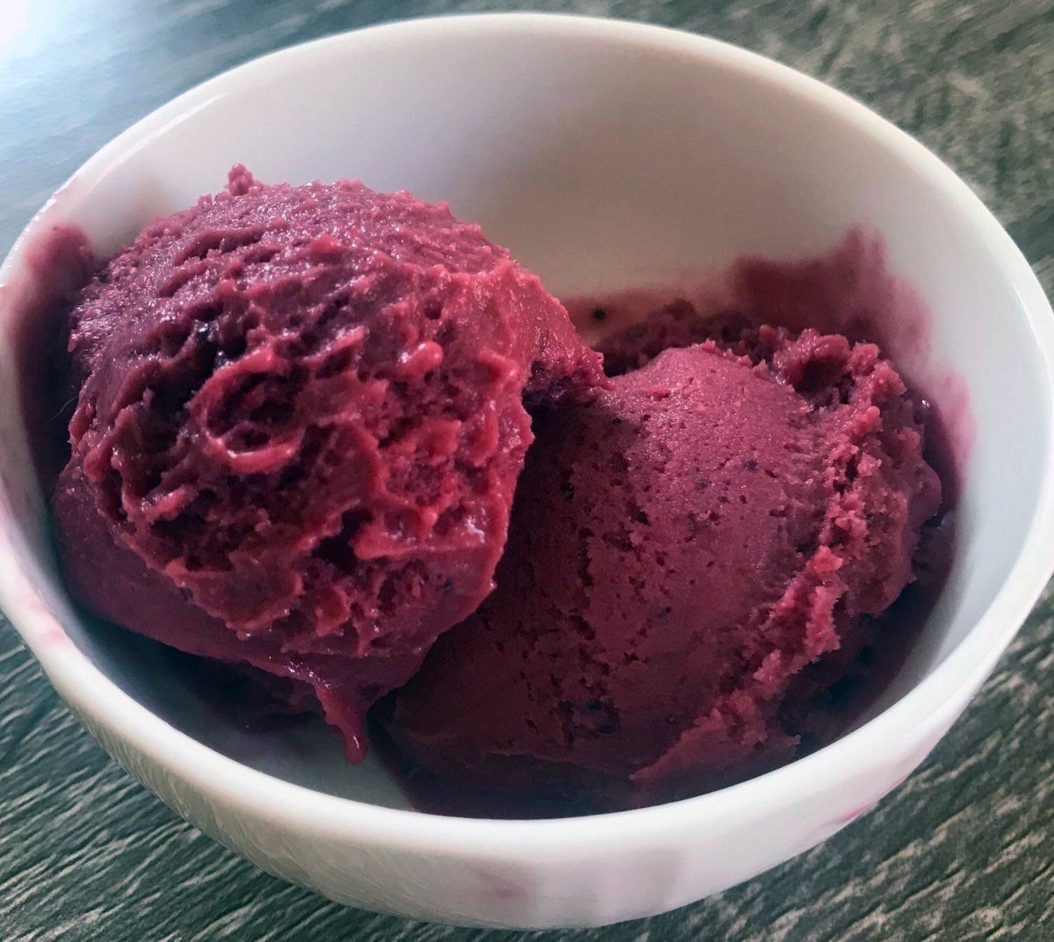 two scoops of blackberry sherbet in a white bowl