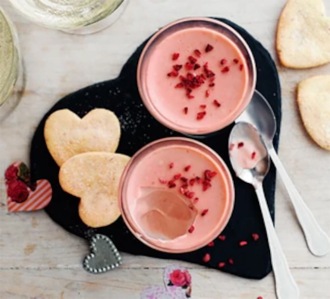 Two champagne-raspberry possets served on a heart-shaped tray with heart-shaped shortbread biscuits