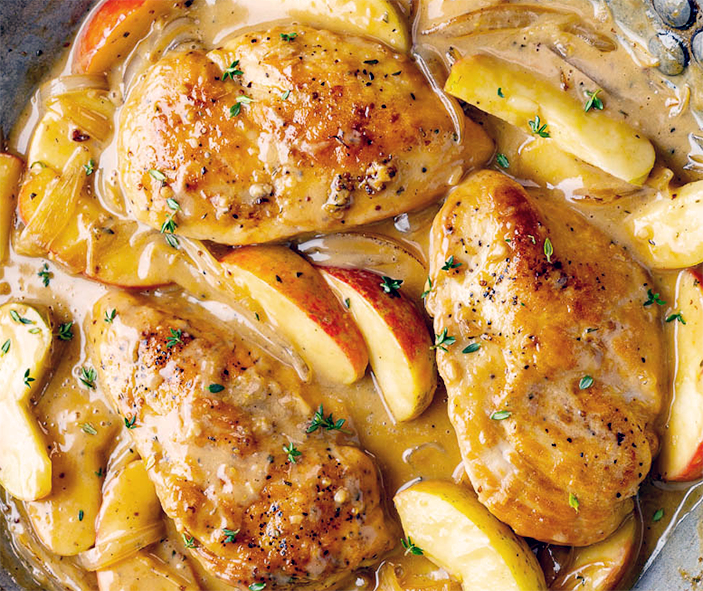 chicken breasts with apple slices in a whisky sauce cooking in a steel pan