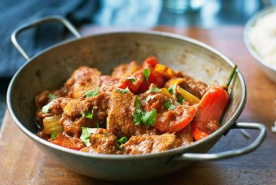 chicken jalfrezi garnished with a red chilli presented in a steel balti dish