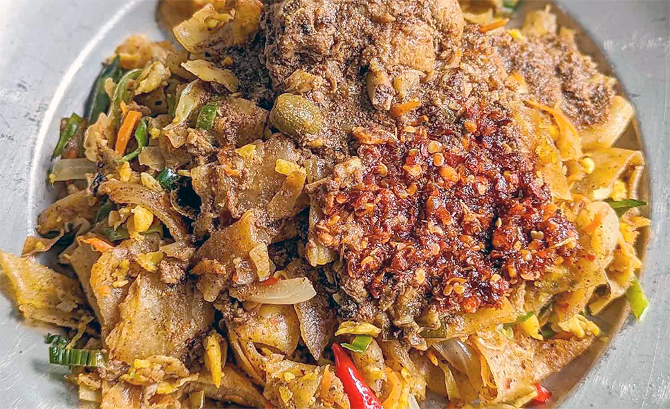 chicken kottu, curry with vegetables, eggs and roti pieces served on a plate