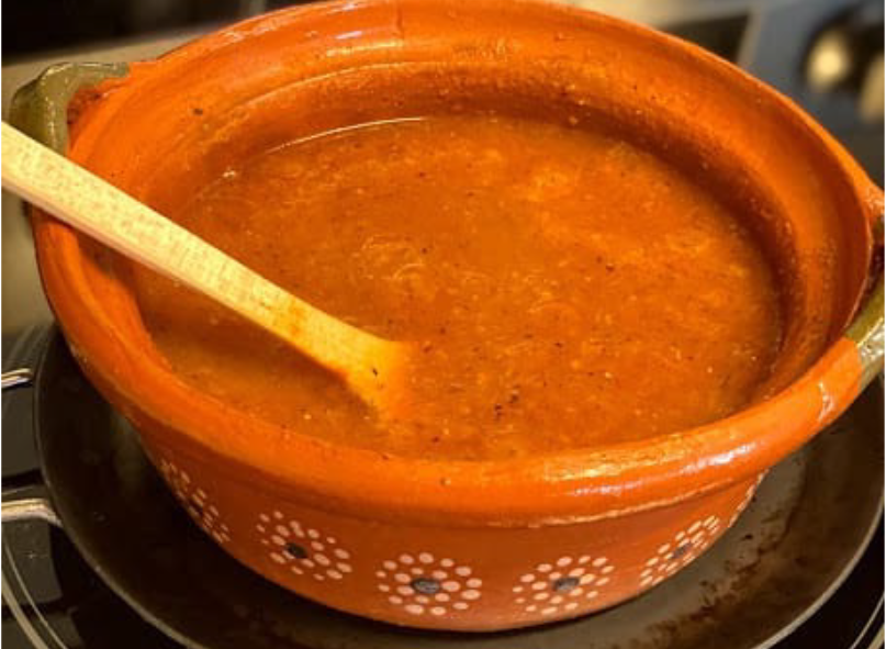 chiltomate salsa in a decorated earthenware bowl with a wooden spoon