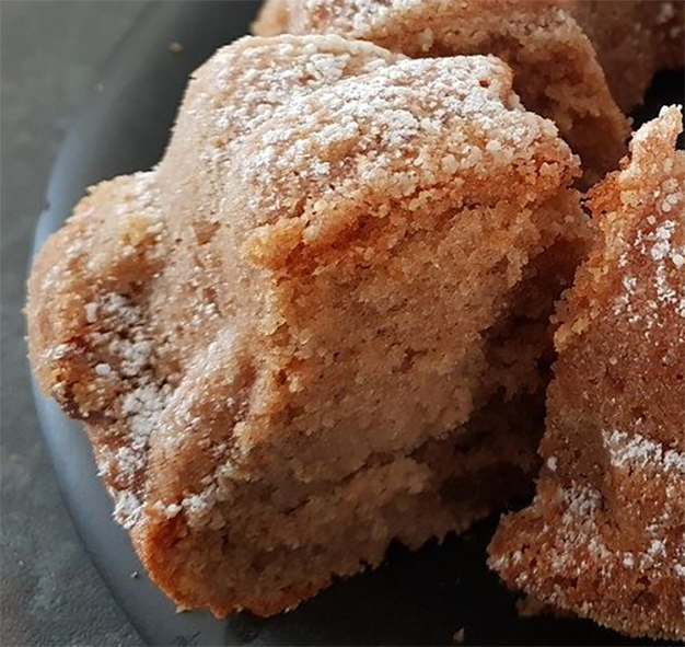 slice of zimt kuchen removed from a whole bundt-style cake dusted with flour and cinnamon