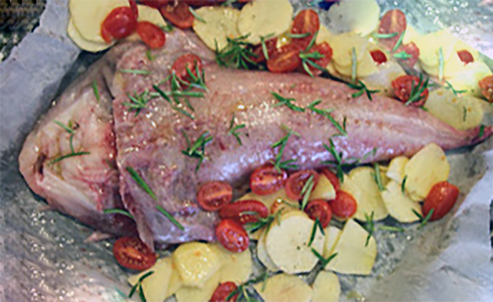 monkfish tail on a bed of sliced potatoes and tomatoes ready to go in the oven
