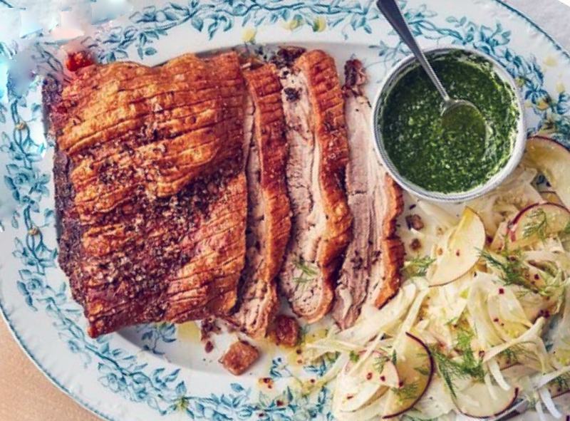 roasted pork belly served on a plate with fennel and apple slaw and a bowl of mojo verde sauce