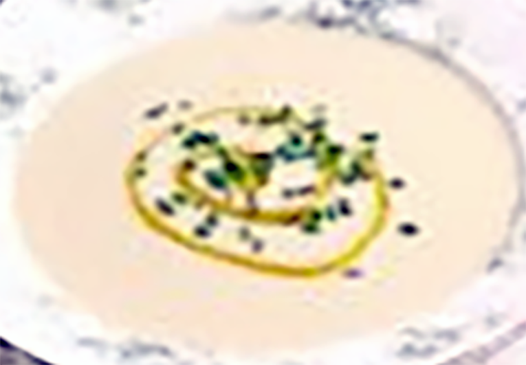 smooth cream of puffball soup served in a bowl served with a drizzle of oil and a sprinkle of chives