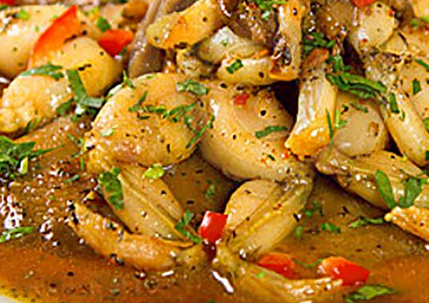 Dominican mountain chicken, frogs's legs in gravy garnished with red bell pepper and coriander leaves on a plate